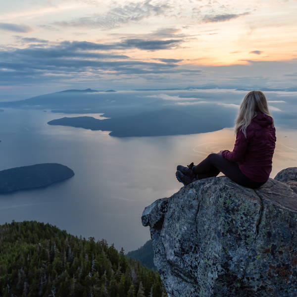 Woman sitting on a high rock overlooking a lake