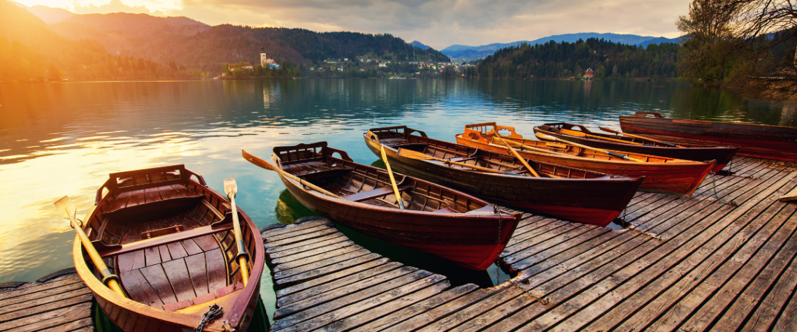 An image of rowboats docked in a still lake
